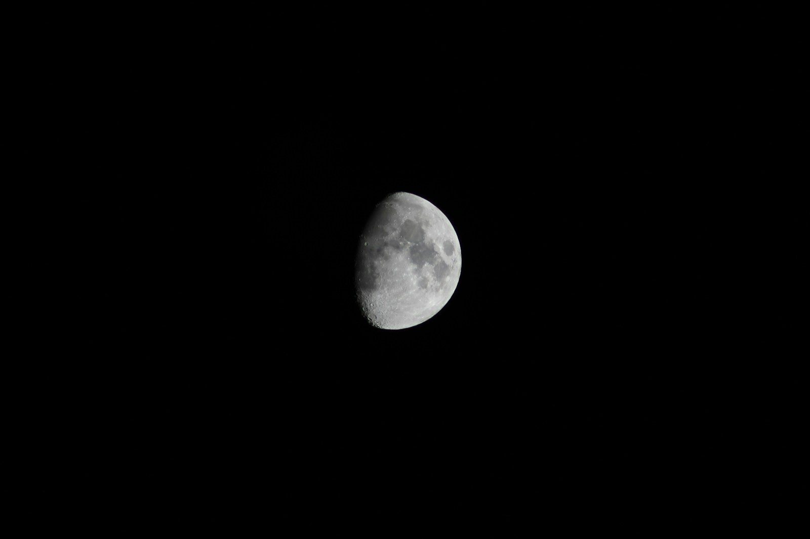 a half moon is seen in the dark sky